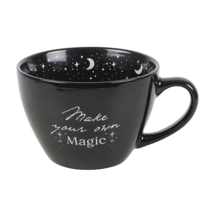 Black mug with star and moon pattern inside and 'Make your own Magic' text on a white background
