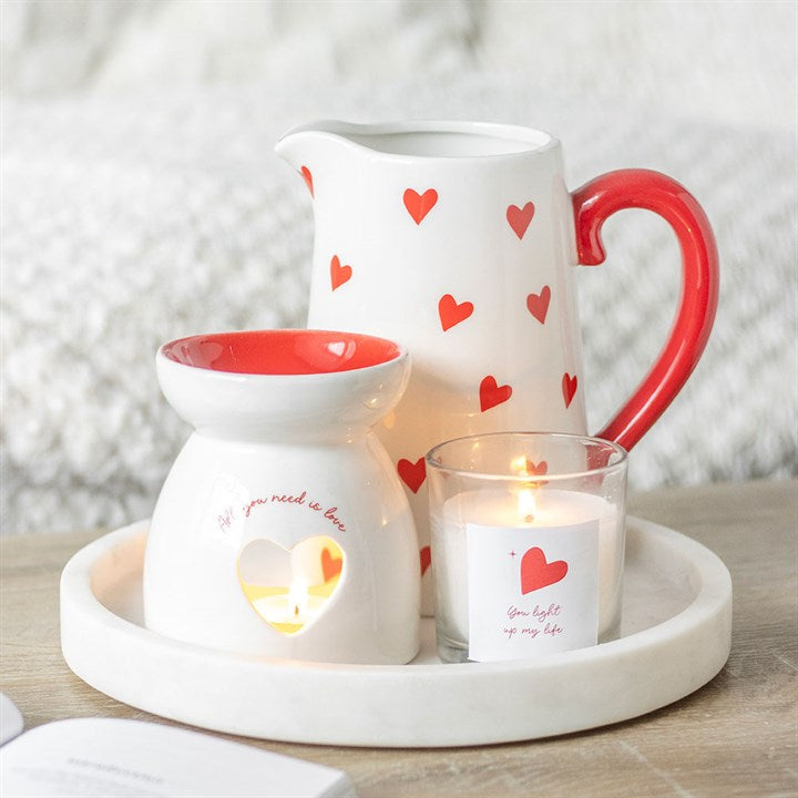 Ceramic valentines Day oil burner gift and candle with heart designs on a tray.