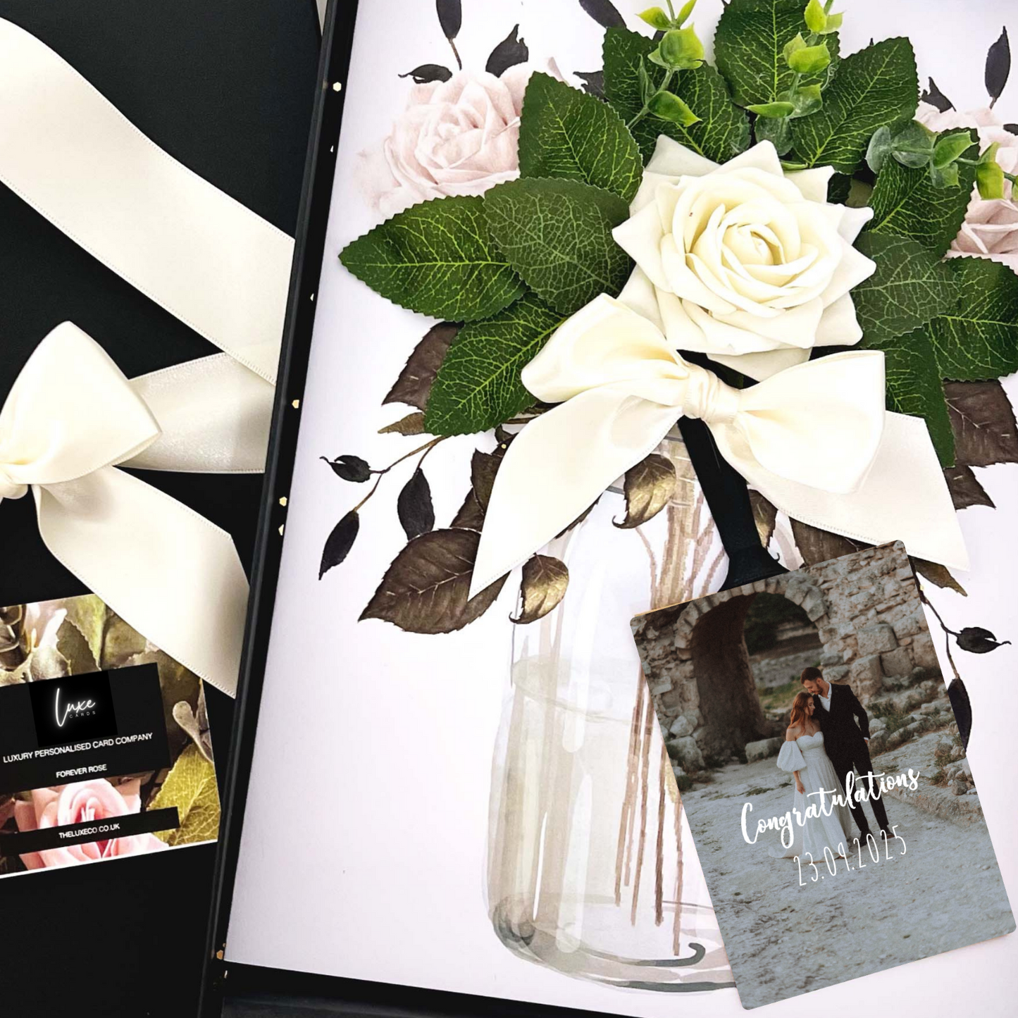 Luxury Personalised Photo Wedding Congratulations Card Floral arrangement with white roses and green leaves, a card, and a box on a white background.