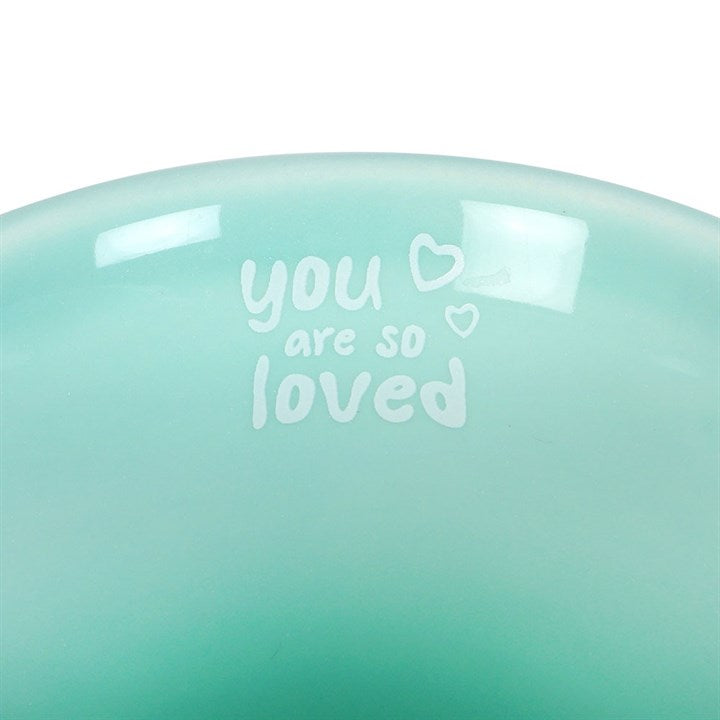 Teal ceramic plate with 'you are so loved' text and heart symbols on a white background