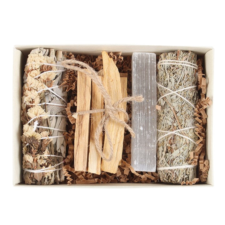 Box containing various types of smudge sticks and tools on a white background