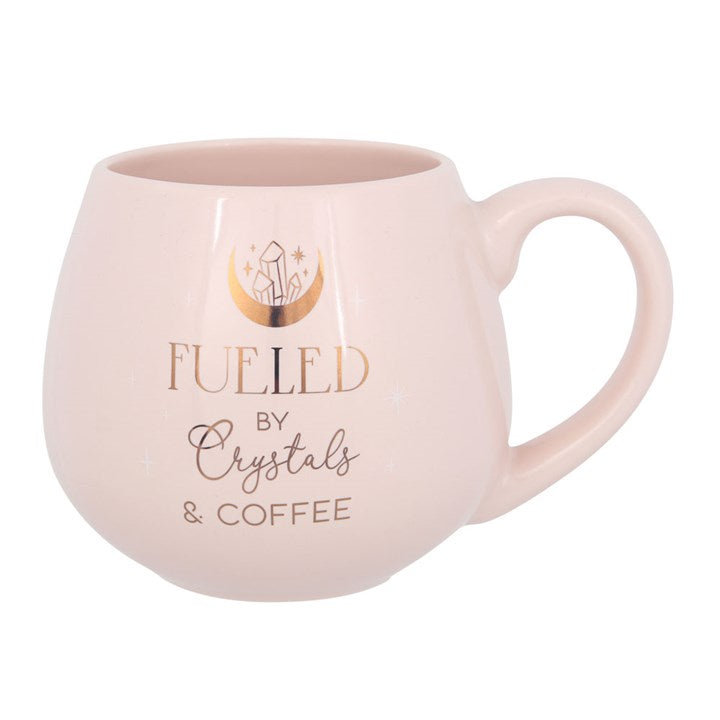Pink mug with 'Fueled by Crystals & Coffee' text and crystal design on a white background