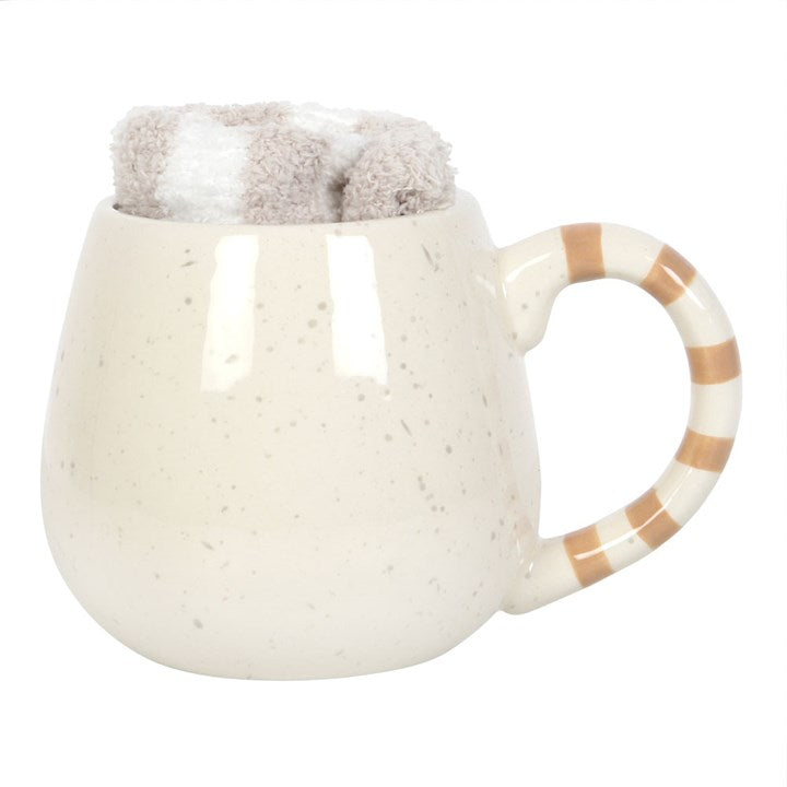 White ceramic mug with a brown handle and fuzzy gray top on a white background