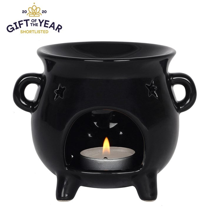 Black ceramic witches cauldron oil burner with a lit candle inside on a white background, shortlisted for 'Gift of the Year'.