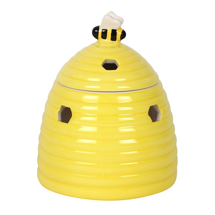 Yellow ceramic bee hive oil burner with a bee on top against a white background