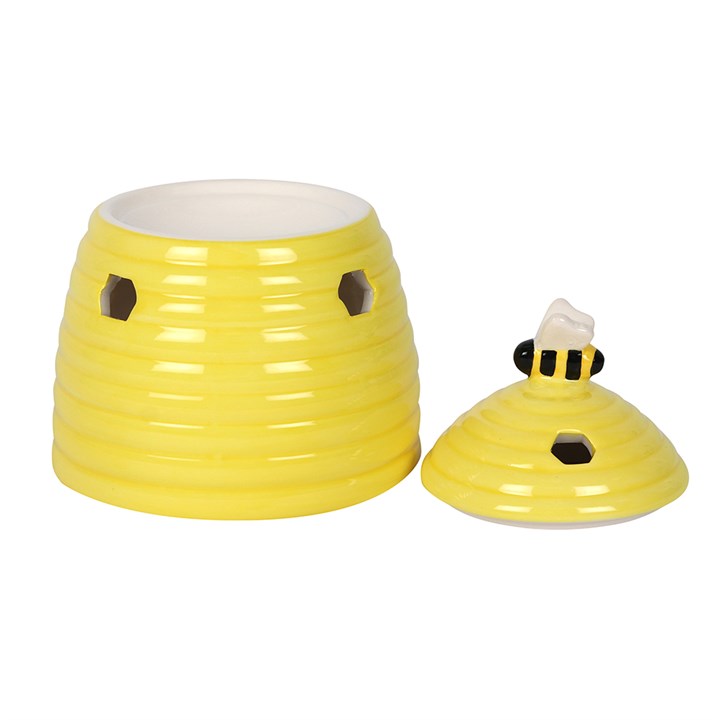 Yellow ceramic beehive-shaped oil burner with a bee design on lid a white background