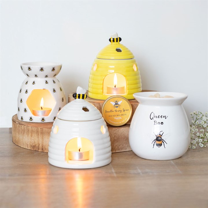 Bee accessories - A Set of ceramic wax warmers with bee designs on a wooden surface.