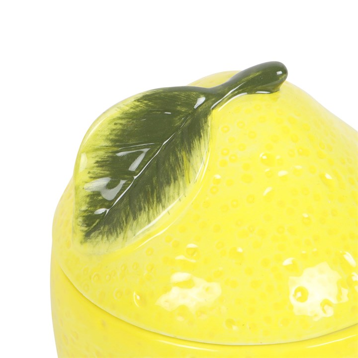 Yellow ceramic lemon wax warmer with a green leaf on a white background