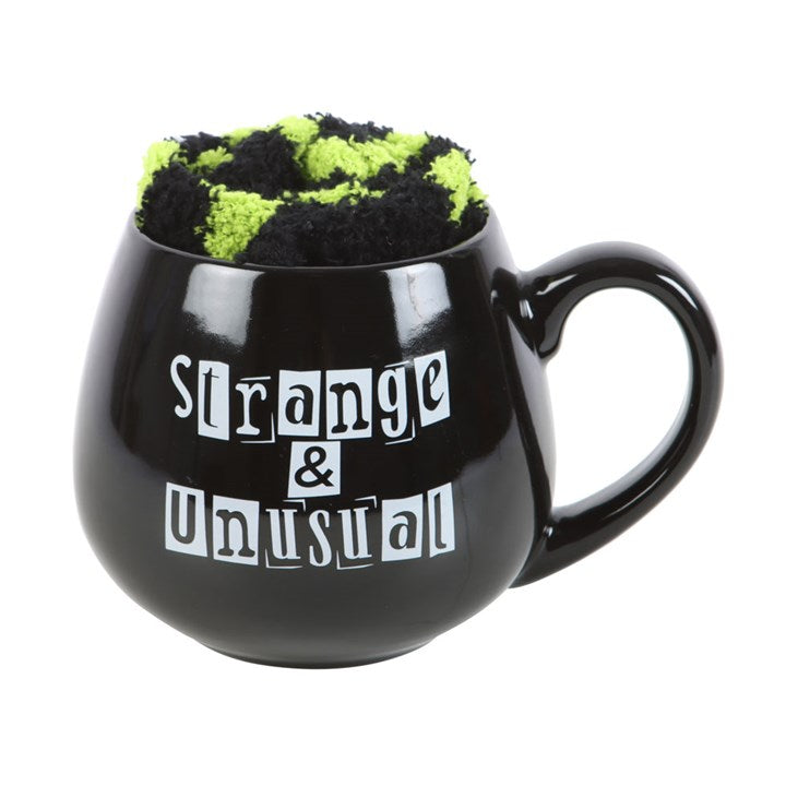 Black mug with text 'Strange & Unusual' and a green and black patterned item inside on a white background