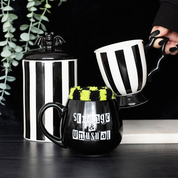 Black and white striped mugs with decorative elements on a dark surface.
