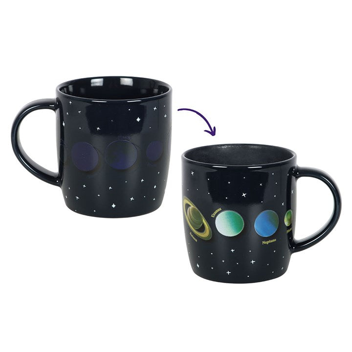 Black mug with starry design on one side and solar system design on the other, with an arrow indicating the transformation.