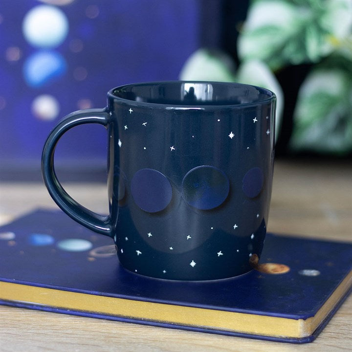 Navy blue mug with celestial design on a notebook
