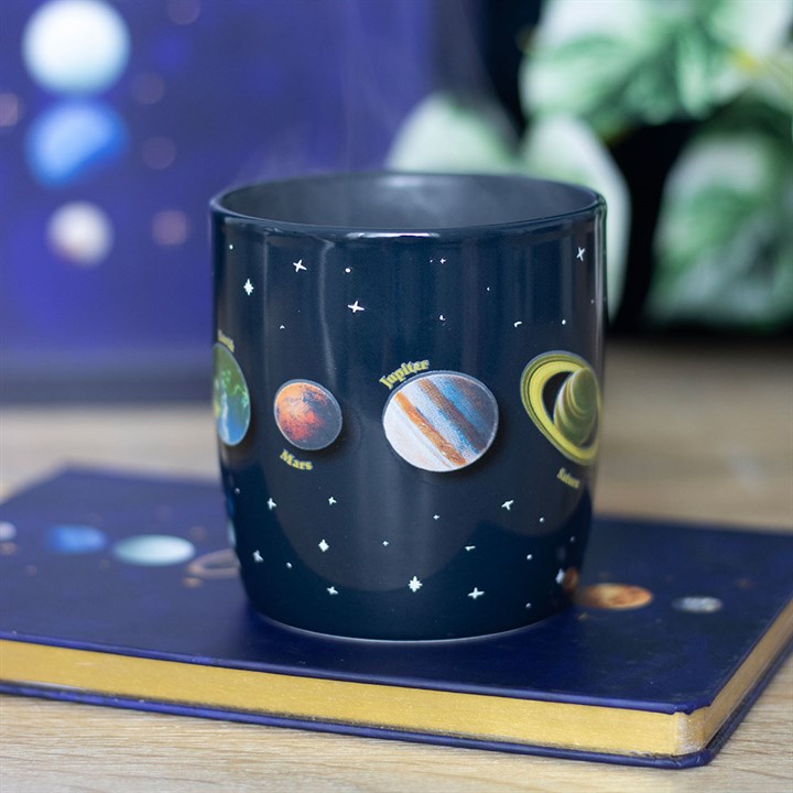 Navy blue mug with solar system design on a wooden surface
