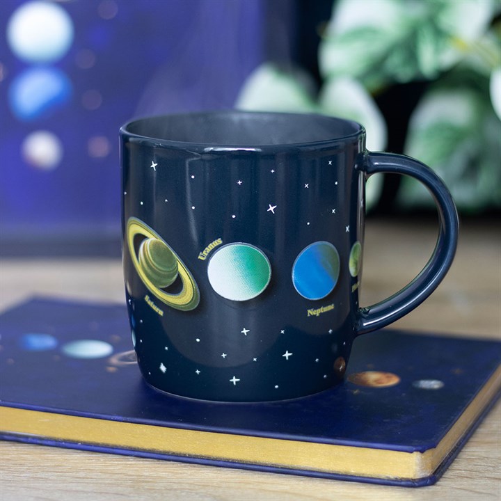 Navy blue mug with solar system designs on a wooden surface