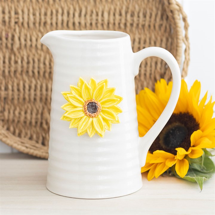 White ceramic pitcher with sunflower design on a wooden surface