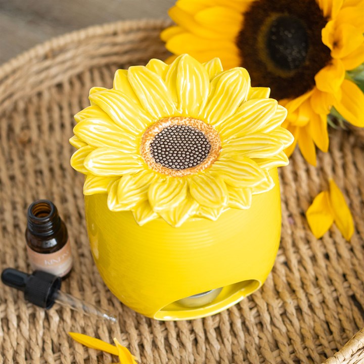 Yellow sunflower-shaped diffuser on a woven surface with a sunflower in the background