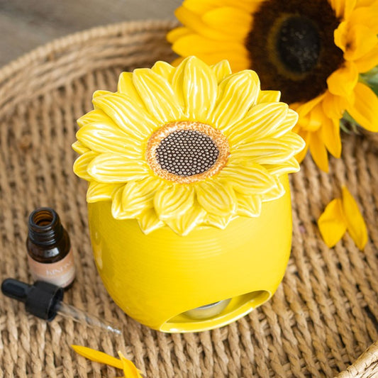 Yellow sunflower-shaped diffuser on a woven surface with a sunflower in the background