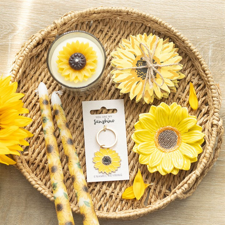 Sunflower-themed products including candles and earrings on a woven tray.