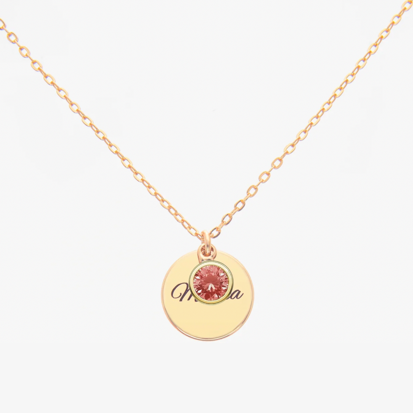 Gold necklace with a round pendant featuring a pink gemstone and engraved name on a white background