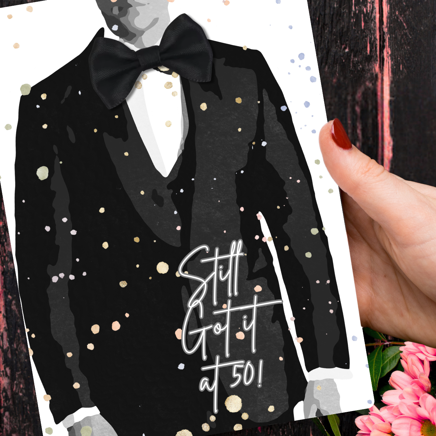 50th Tux Birthday Card for him - Black tuxedo with bow tie and 'Still Got It at 50!' text on a decorative card held by a hand.
