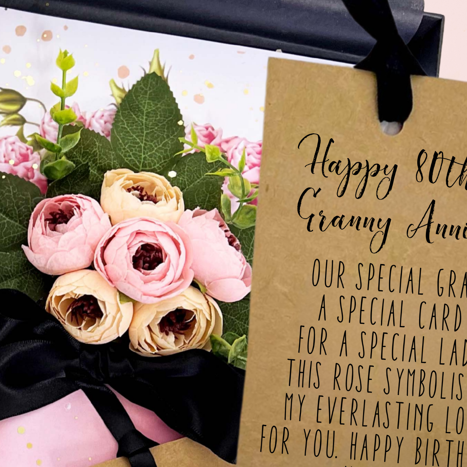 Bouquet of flowers with a gift box and 'Happy 80th Granny' card on a light pink background