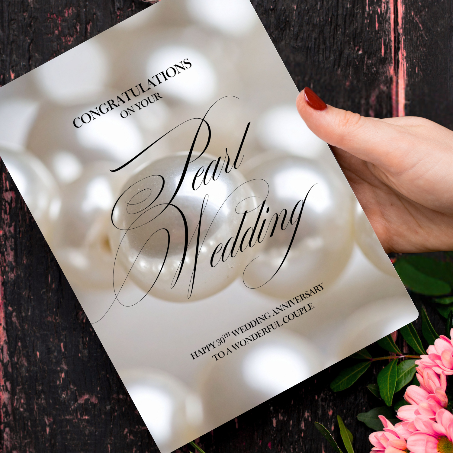 A5 30th Pearl Anniversary Card - Hand holding a card with 'Pearl Wedding' text and pearl imagery on a dark surface with flowers.