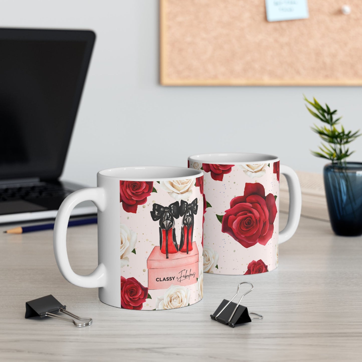 Two mugs with floral and high-heeled shoe design on a desk with office items.