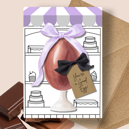 Personalised Chocolate Scented Handmade Easter Card- Greeting card with chocolate egg and bow, featuring a tag with text, on a decorative background.