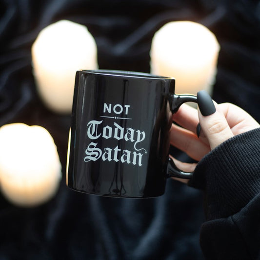 Black mug with 'Not Today Satan' text held by a hand against a blurred candlelit background