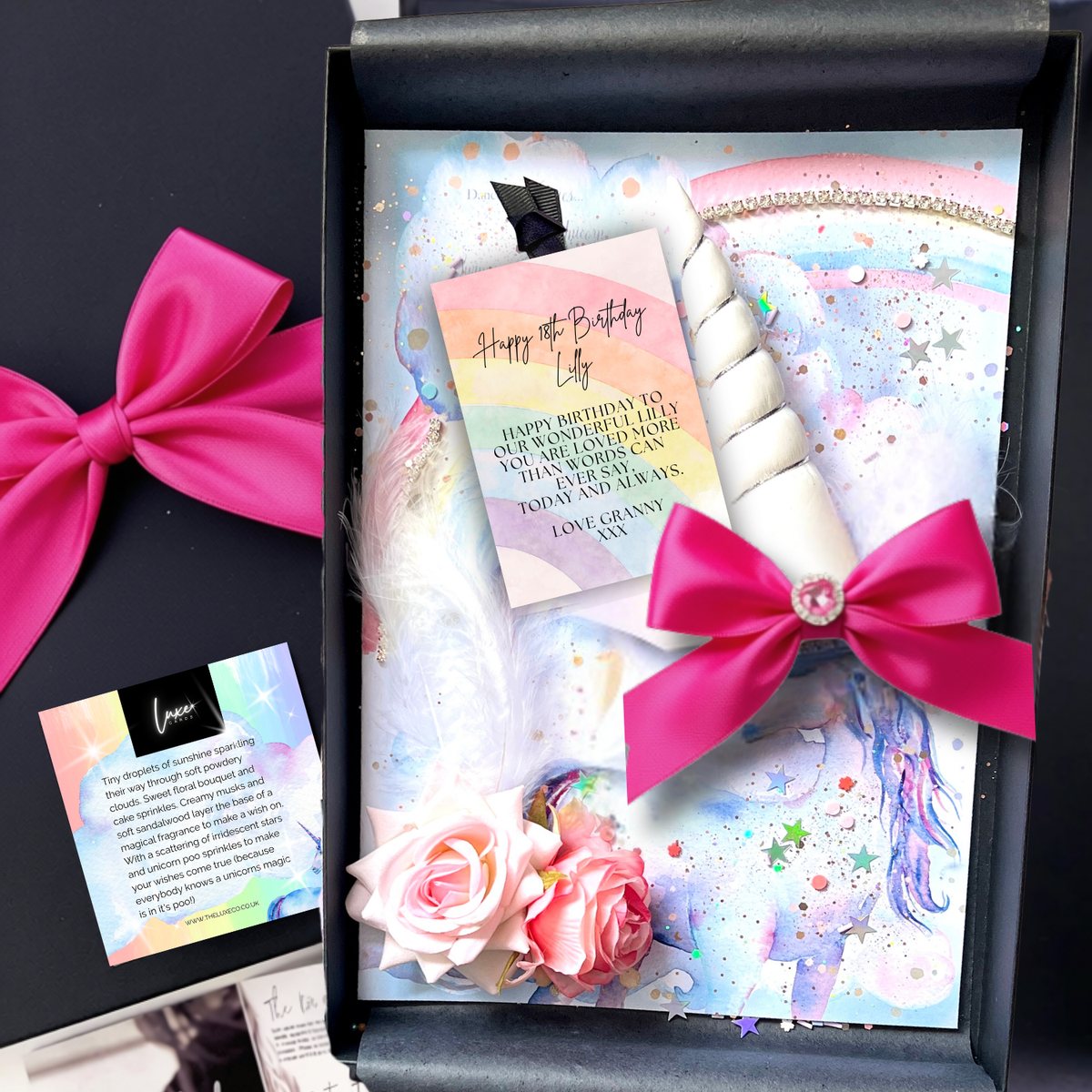 A luxury 18th personalised unicorn birthday gift with black gift box containing a personalized unicorn-themed birthday card set with a white unicorn horn, bright pink satin bows, pastel watercolor background, stars, feathers, and small roses. 