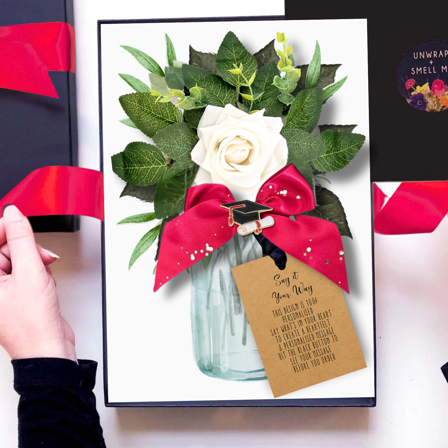 Luxury Graduation Cards handmade and personalised by Luxe Cards with a Bouquet of flowers with a white rose, green leaves, and a red bow in a clear vase on a white background.
