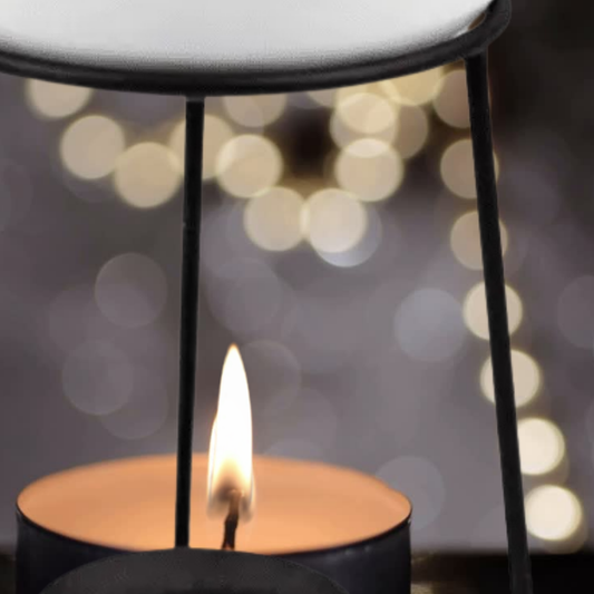 Candle in a black and white oil burner holder on a blurred background with fairylights