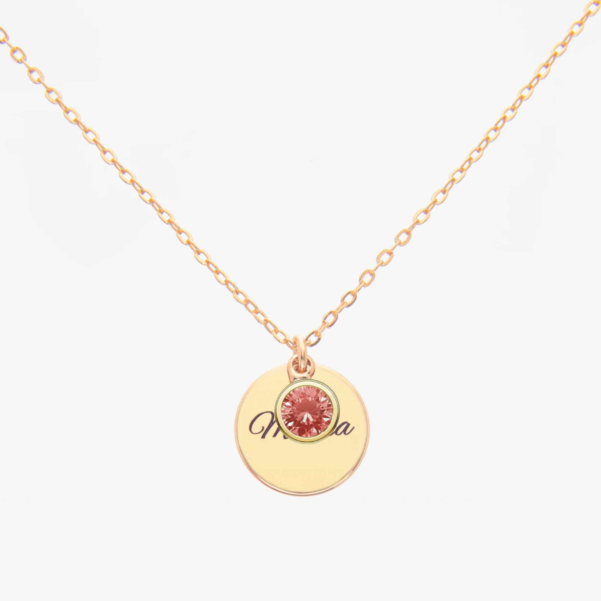 Gold necklace with a round pendant featuring a pink gemstone and engraved name on a white background