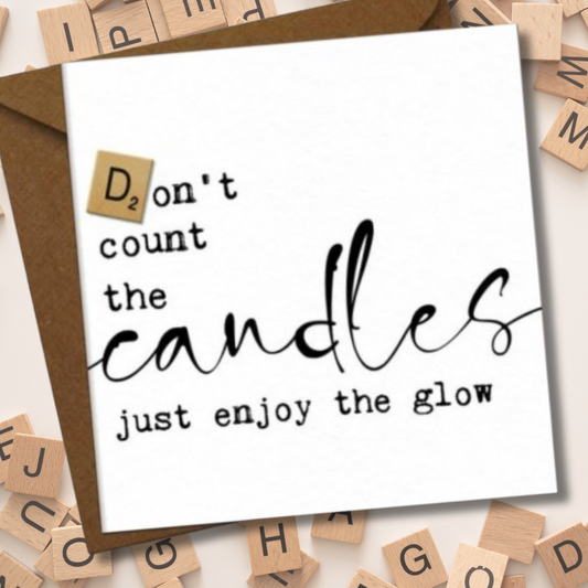 Card with 'Don't count the candles, just enjoy the glow' text surrounded by scrabble tiles.